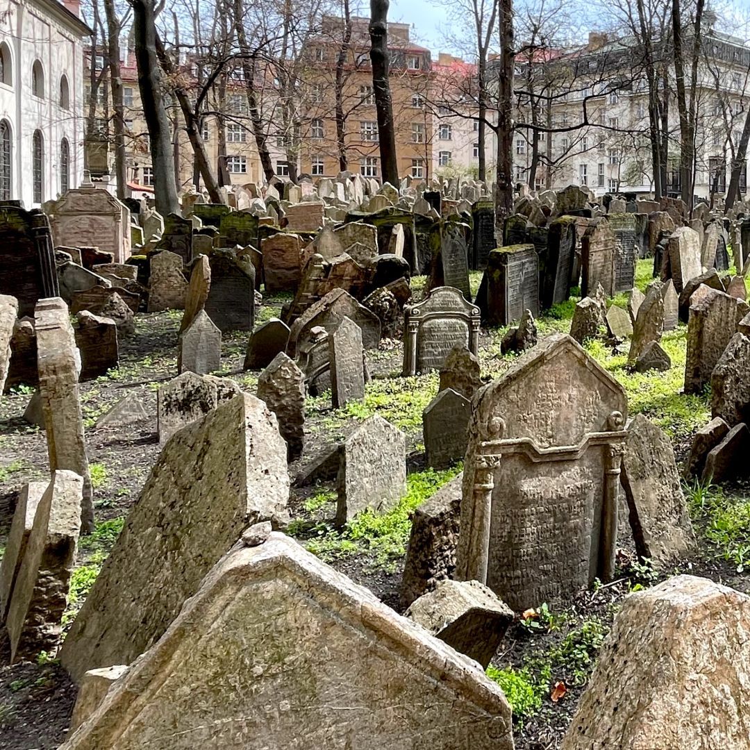 This somber image shows the dense thicket of weathered gravestones at Prague’s Old Jewish Cemetery. The stones, some leaning and overlapping, reflect centuries of burials in a limited space. Trees rise among them, and the scene is filled with history and quiet reverence in the heart of the Jewish Quarter.